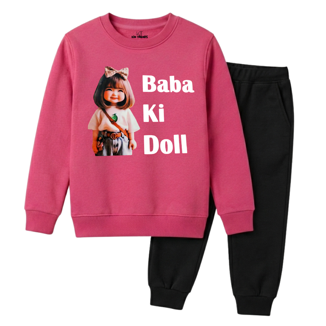 A kids' two-piece sweatshirt and jogger pants set. The sweatshirt is a vibrant pink with a graphic of a doll and the text 'Baba Ki Doll' in white.